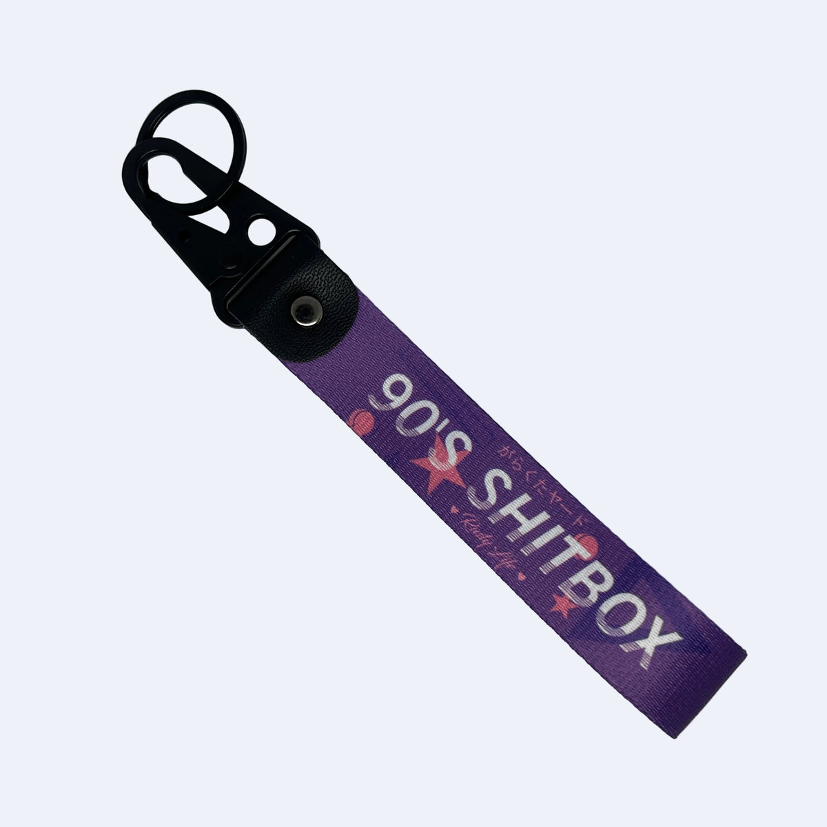 A purple fabric keychain strap with a black plastic carabiner and metal snap, featuring the text '90'S SHITBOX' in white with pink star accents.