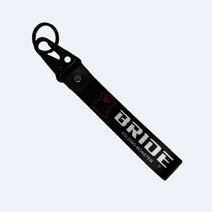 Black key tag with BRIDE HOLDING MONSTER branding in white print – Motorev embroidered car keychain