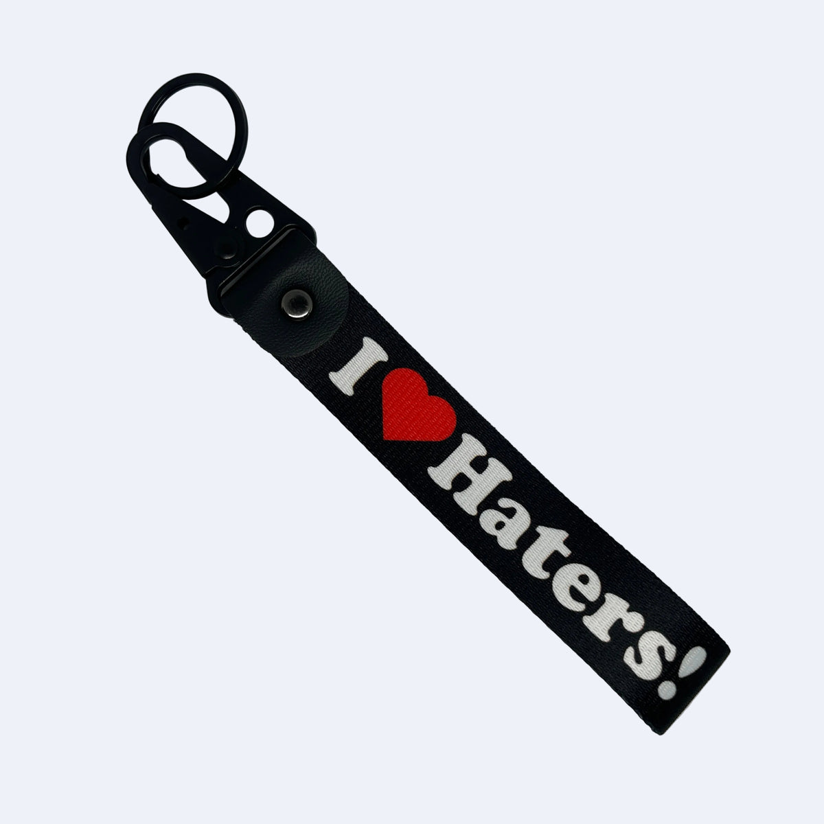 A black keychain strap featuring the text 'I' followed by a red heart and 'Haters!' in white, attached to a black metal key ring on a plain light gray background.