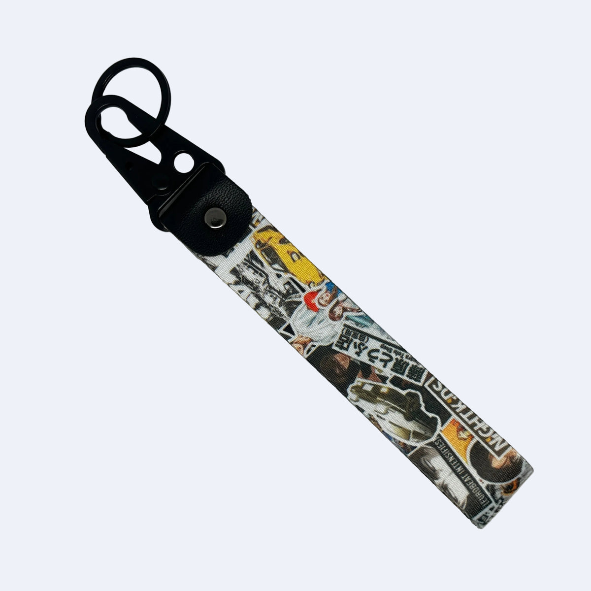 A rectangular keychain or bag strap with a black plastic key ring and snap closure, featuring a collage print of various stickers in black, white, yellow, and red on a light gray background.