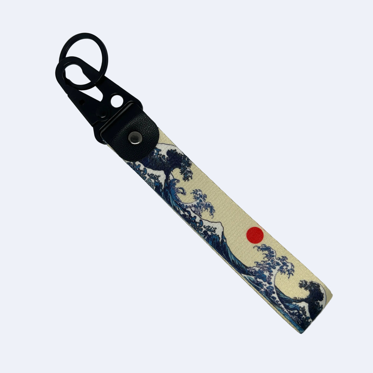 A canvas keychain strap featuring a blue and cream print of 'The Great Wave off Kanagawa' with a small red sun, attached to a black leather key ring clip.