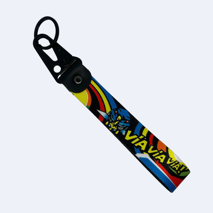 A black fabric wrist strap keychain with a colorful graphic print featuring a blue shark and the text 'VIA VIA VIA' on a light gray background.