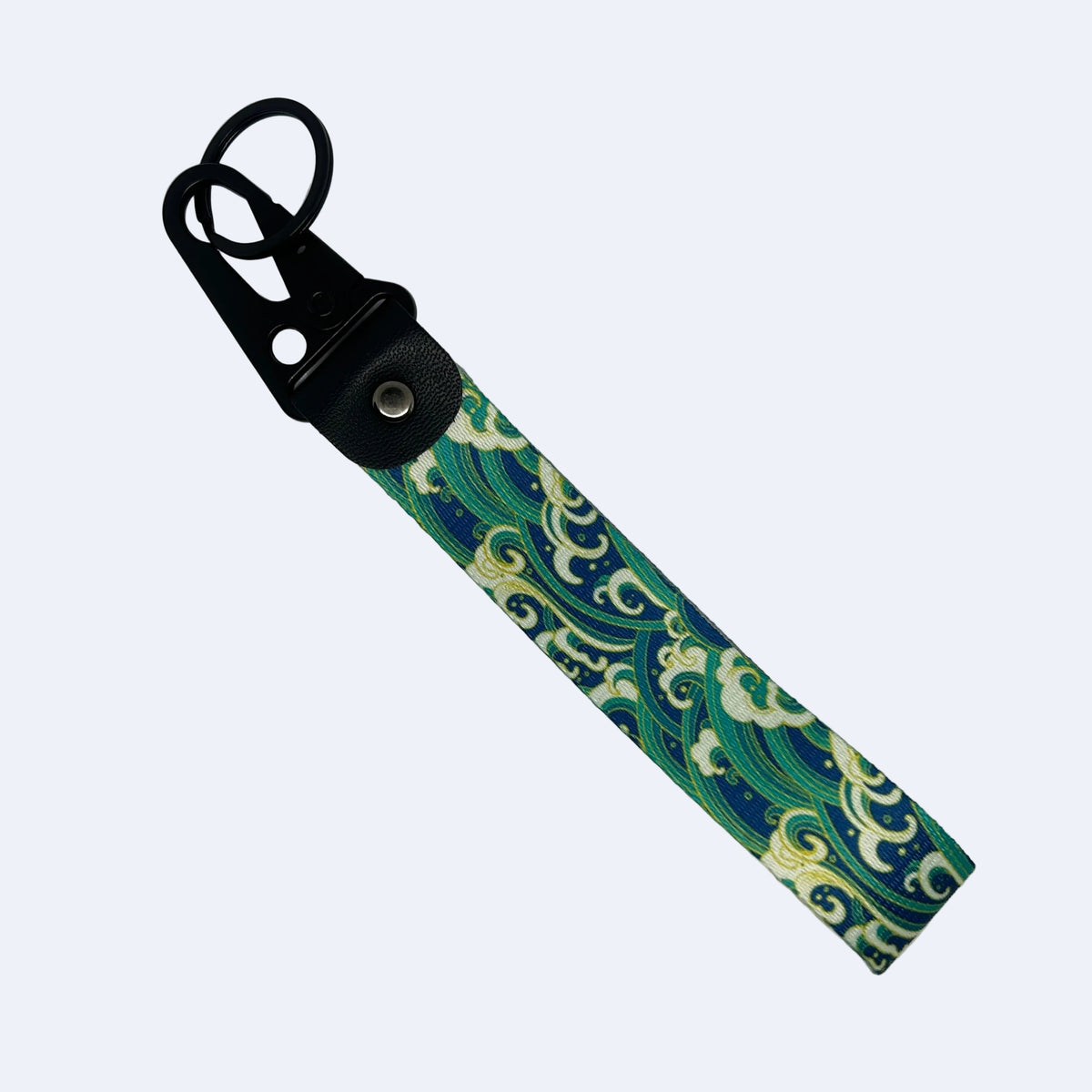 A fabric wrist strap keychain featuring a green and blue wave pattern, attached to a black plastic clip with a silver metal snap button, shown on a light gray background.