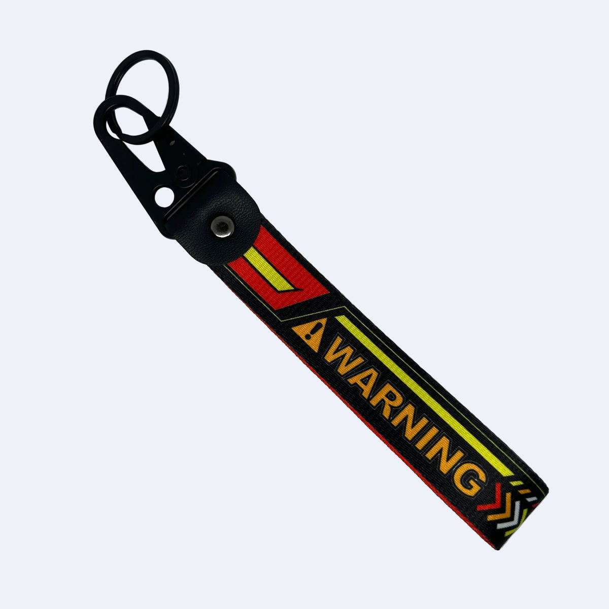 A black rubber strap keychain with a metal snap hook and key ring, featuring a bold yellow and red graphic with the word 'WARNING' printed on it, set against a plain light gray background.